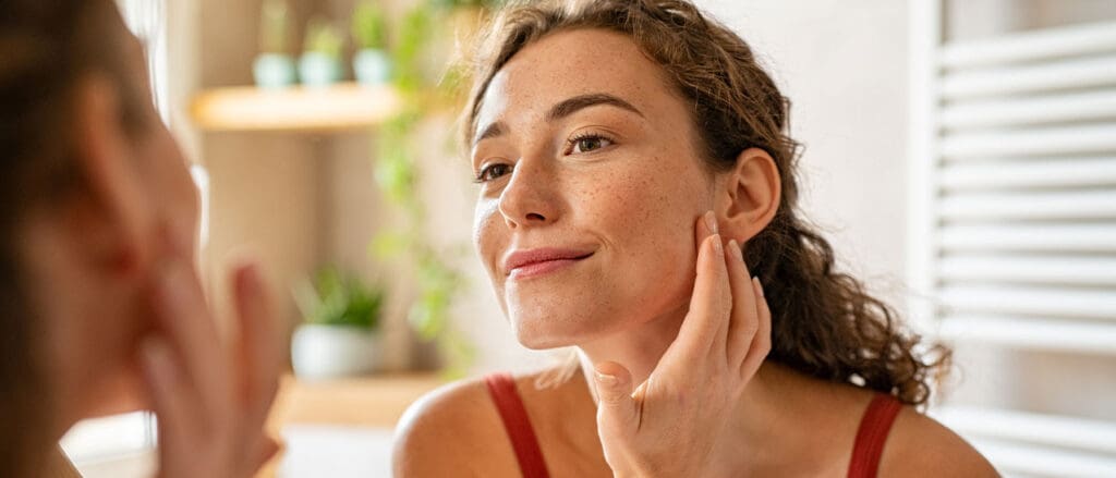 Woman Putting on Face Cream with Freckles